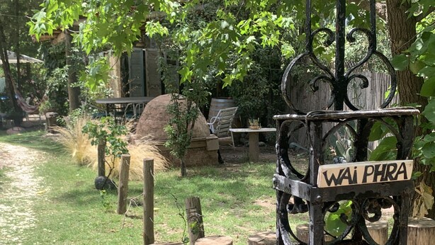 A rustic outdoor area with a wooden fence, a sign reading "Wai Phra", and a stone structure in the background. - Holiday Home Mendoza Leisure Time (Luján de Cuyo)