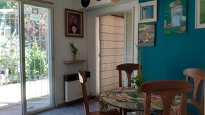 A dining area with a glass table, wooden chairs, a floral tablecloth, and a blue accent wall with artwork. - Holiday Home Mendoza Leisure Time (Luján de Cuyo)