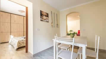 Une pièce comprenant un lit, une table à manger avec des chaises, une armoire en bois et un tableau accroché au mur.