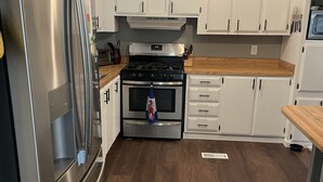 A modern kitchen with white cabinets, stainless steel appliances, and wooden flooring. - Desert Hideaway (Glendale)