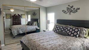 A bedroom with a large bed, a ceiling fan, a dresser, and a mirror. - Desert Hideaway (Glendale)