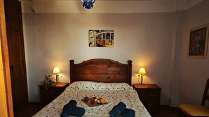 Una camera da letto con un letto in legno, due comodini con lampade, una piccola sedia e un quadro appeso al muro.