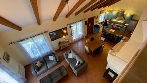 A spacious living area with a sofa set, a dining table, and a kitchen in the background.