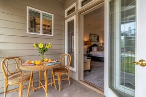 Ein Korbstuhl-Tisch mit Stühlen und einer Blumenvase auf einer Veranda.