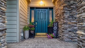 Une entrée de maison avec une porte de couleur turquoise, des murs en pierre et une boîte aux lettres.