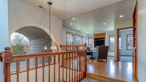 Un intérieur spacieux avec un escalier en bois, de grandes fenêtres et une vue sur l’extérieur.