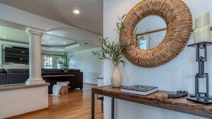 Un salon moderne avec un plancher en bois, un grand miroir, une console et un canapé noir.