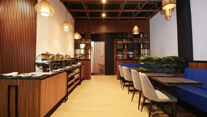 A modern restaurant interior with a long counter, seating area, and decorative lighting.