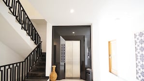 A modern interior with a staircase, a hallway leading to a room, and a patterned wall.