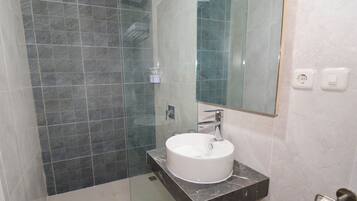 A modern bathroom with a glass-enclosed shower, a white sink, and a large mirror.