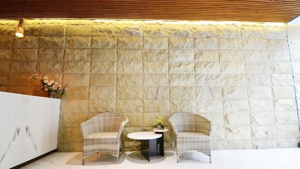 A reception area with a stone wall, two wicker chairs, a small round table, and a reception desk.