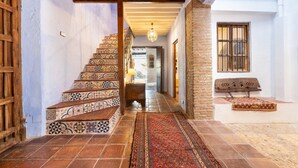 Una escalera con baldosas estampadas, un banco de madera y una alfombra.