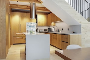 Une cuisine moderne avec des meubles en bois, un îlot central et un escalier menant à un niveau supérieur.