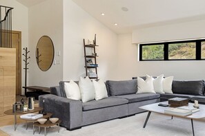 A modern living room with a grey sofa, a coffee table, and a bookshelf.