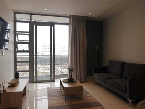 A modern living room with a sofa, a coffee table, and a TV on the wall.