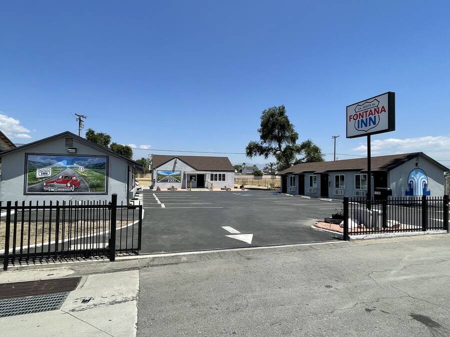 A parking lot with a motel named Fontana Inn, a mural of a car on a road, and a sign for Route 66.