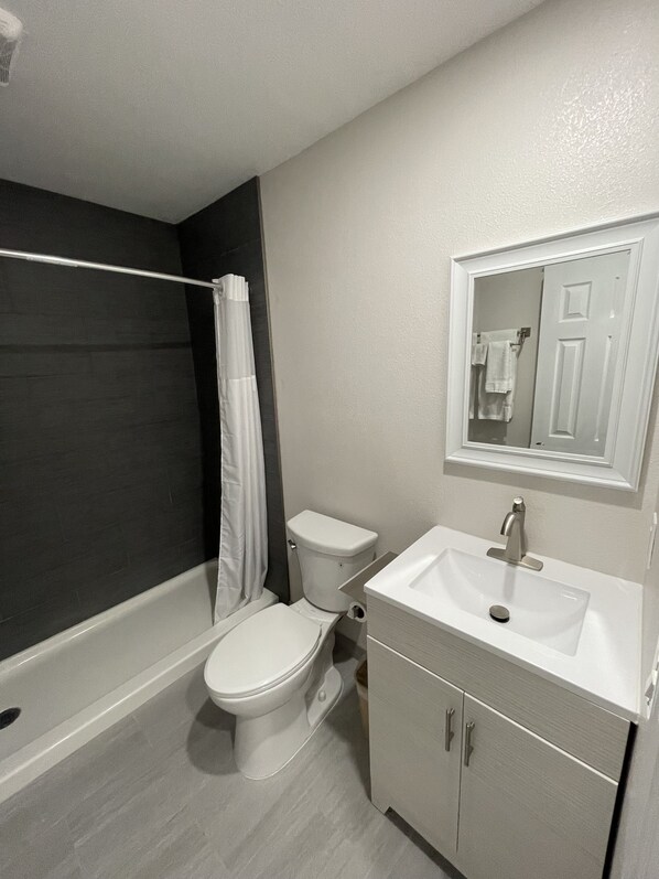A modern bathroom with a shower, toilet, and sink.