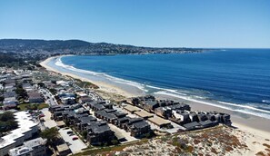 A coastal residential area with a beach, houses, and a clear view of the ocean.