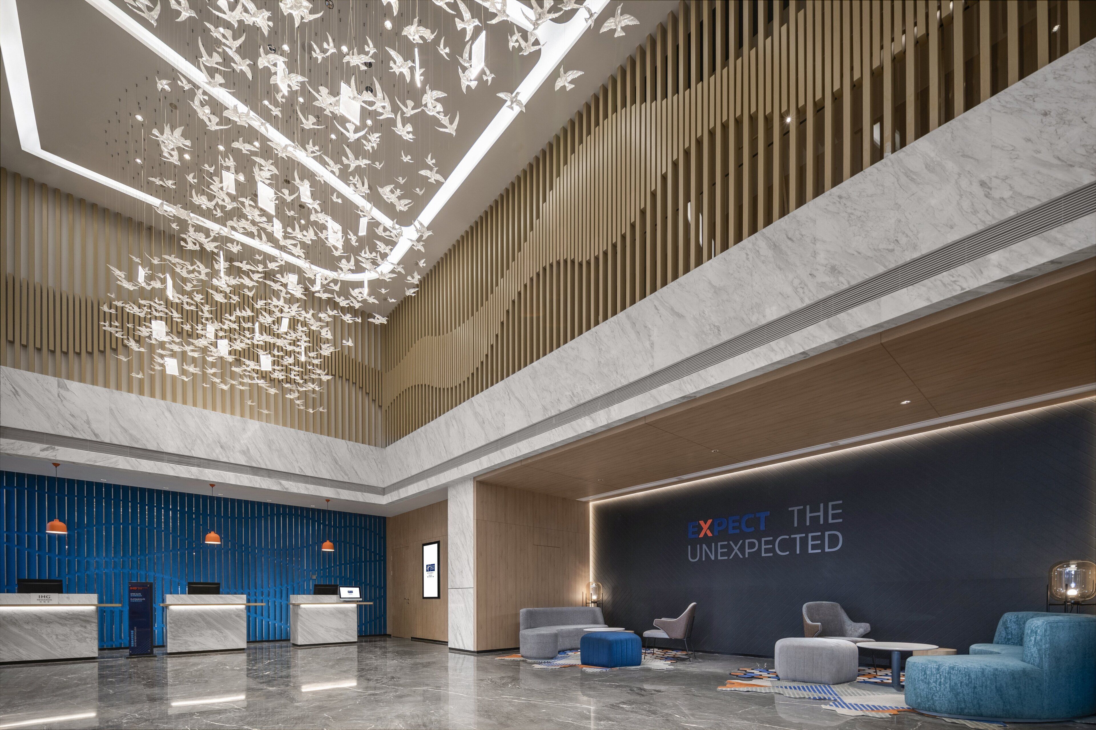 Un vestíbulo moderno con mostrador de recepción, zona de estar y una pared grande con el texto "EXPECT THE UNEXPECTED".