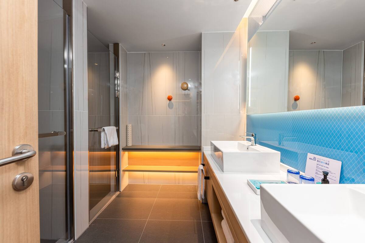 A modern bathroom with a glass shower, two sinks, and a large mirror.