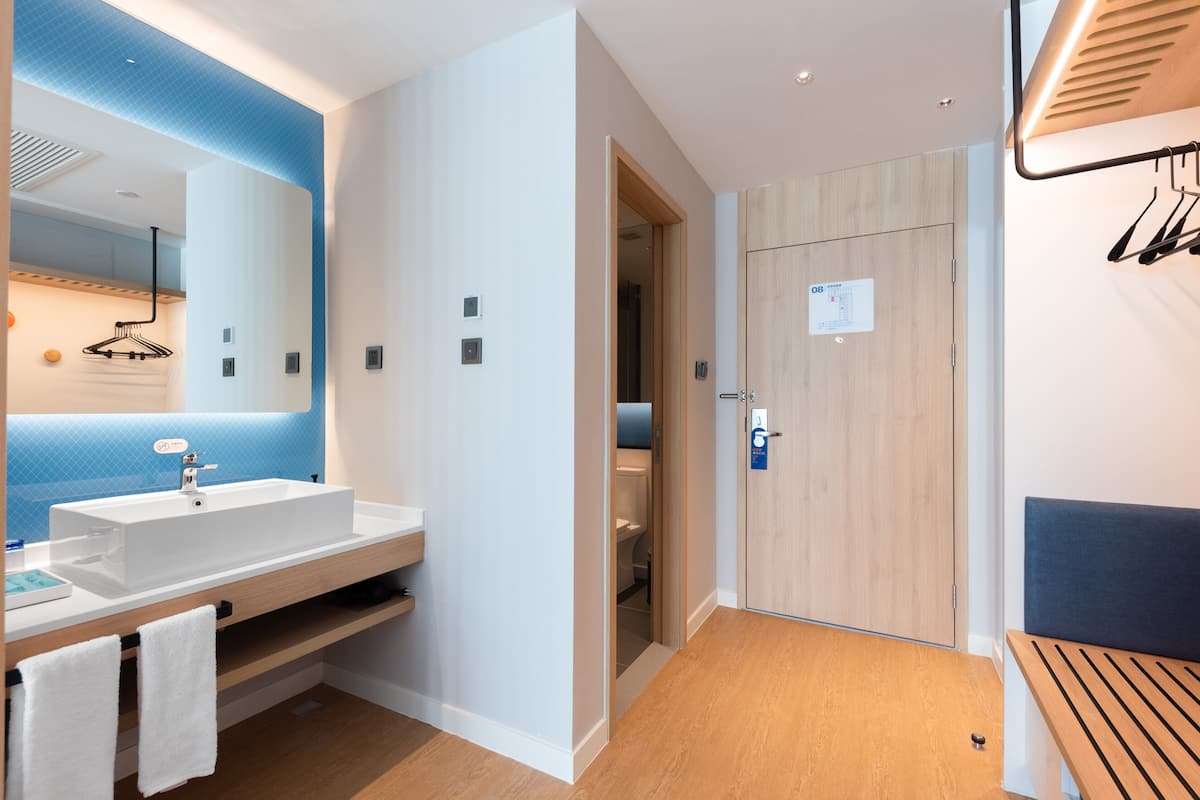A modern bathroom with a large mirror, white sink, and wooden vanity.