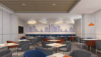 A modern restaurant with multiple tables and chairs, a cityscape mural on the wall, and pendant lighting.