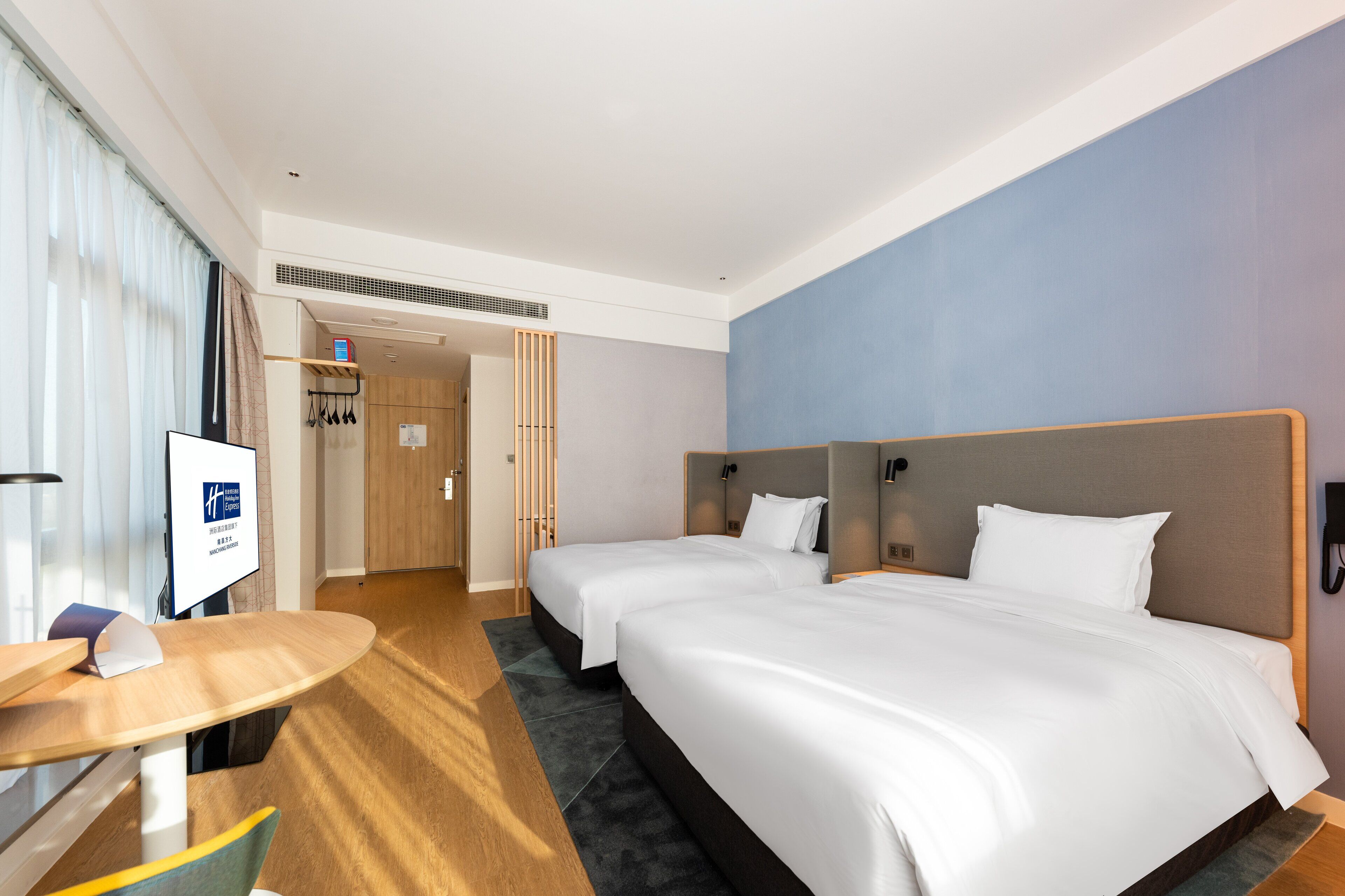Habitación de hotel con dos camas, un escritorio y televisión.