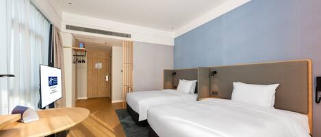 Habitación de hotel con dos camas, un escritorio y televisión.