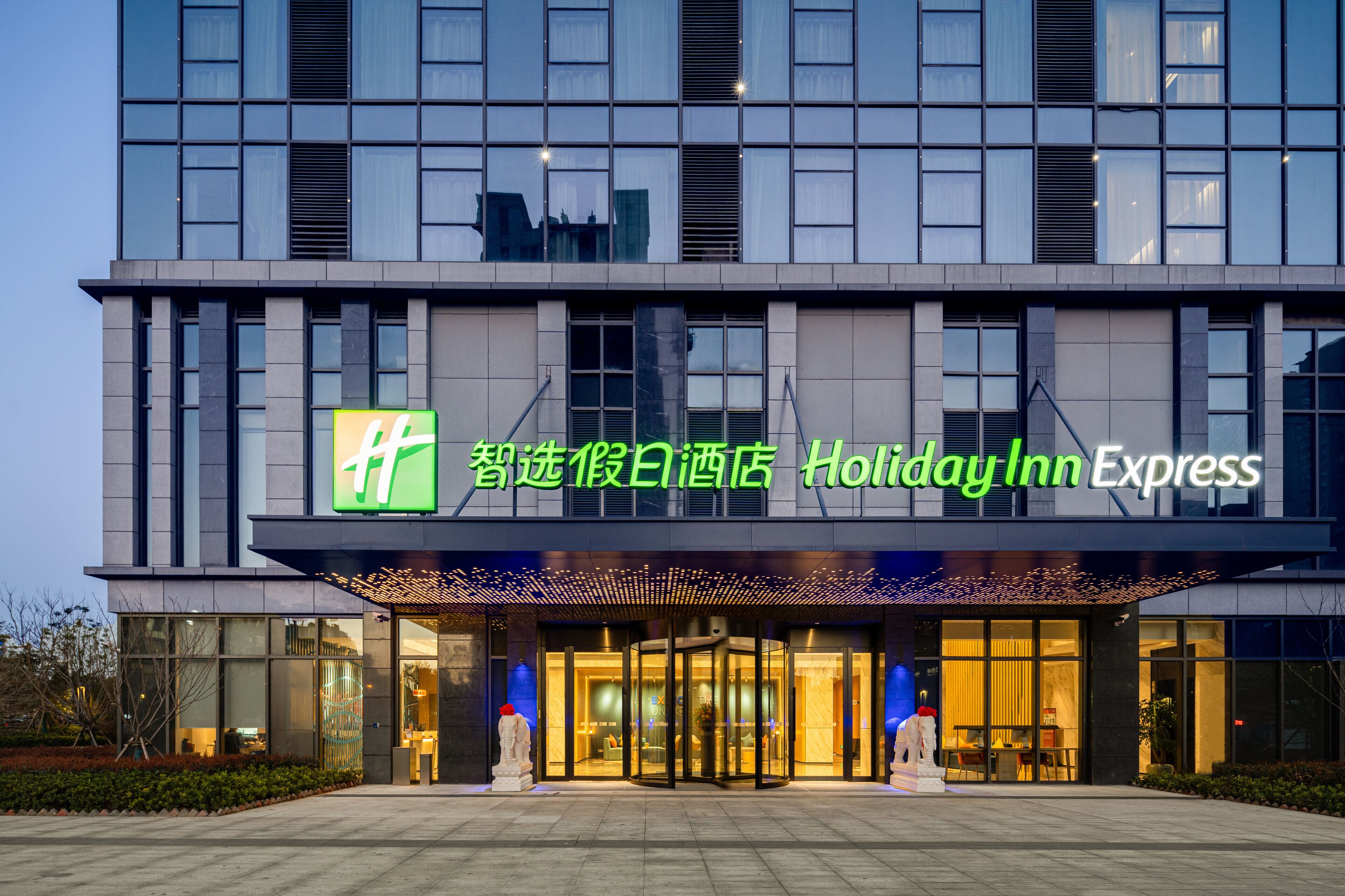 A Holiday Inn Express hotel with a modern facade, large windows, and a prominent entrance with a revolving door.