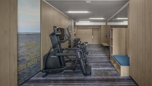 A gym with treadmills, stationary bikes, and a bench.