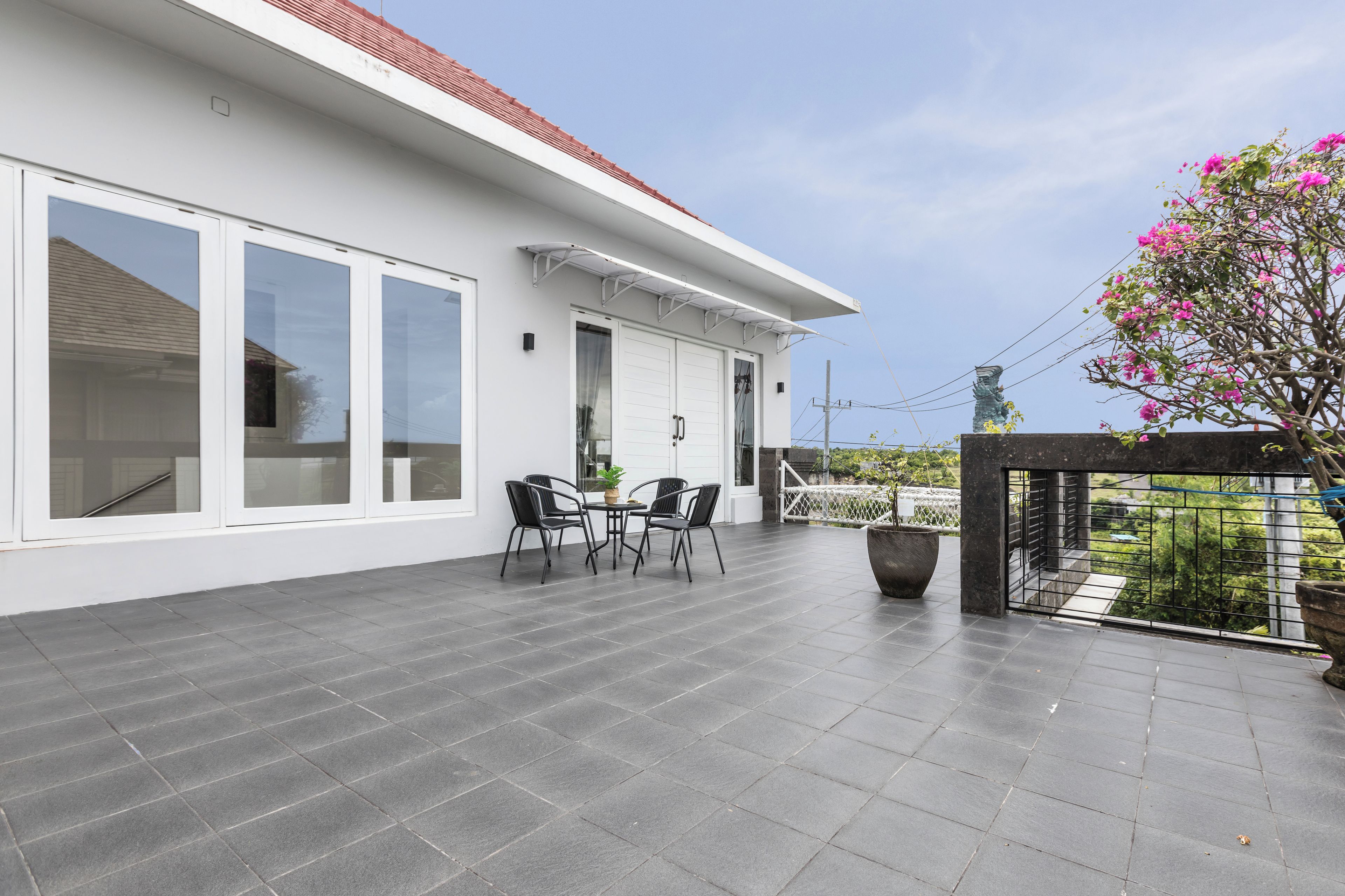 A modern house with a patio, large windows, and a view of the garden.