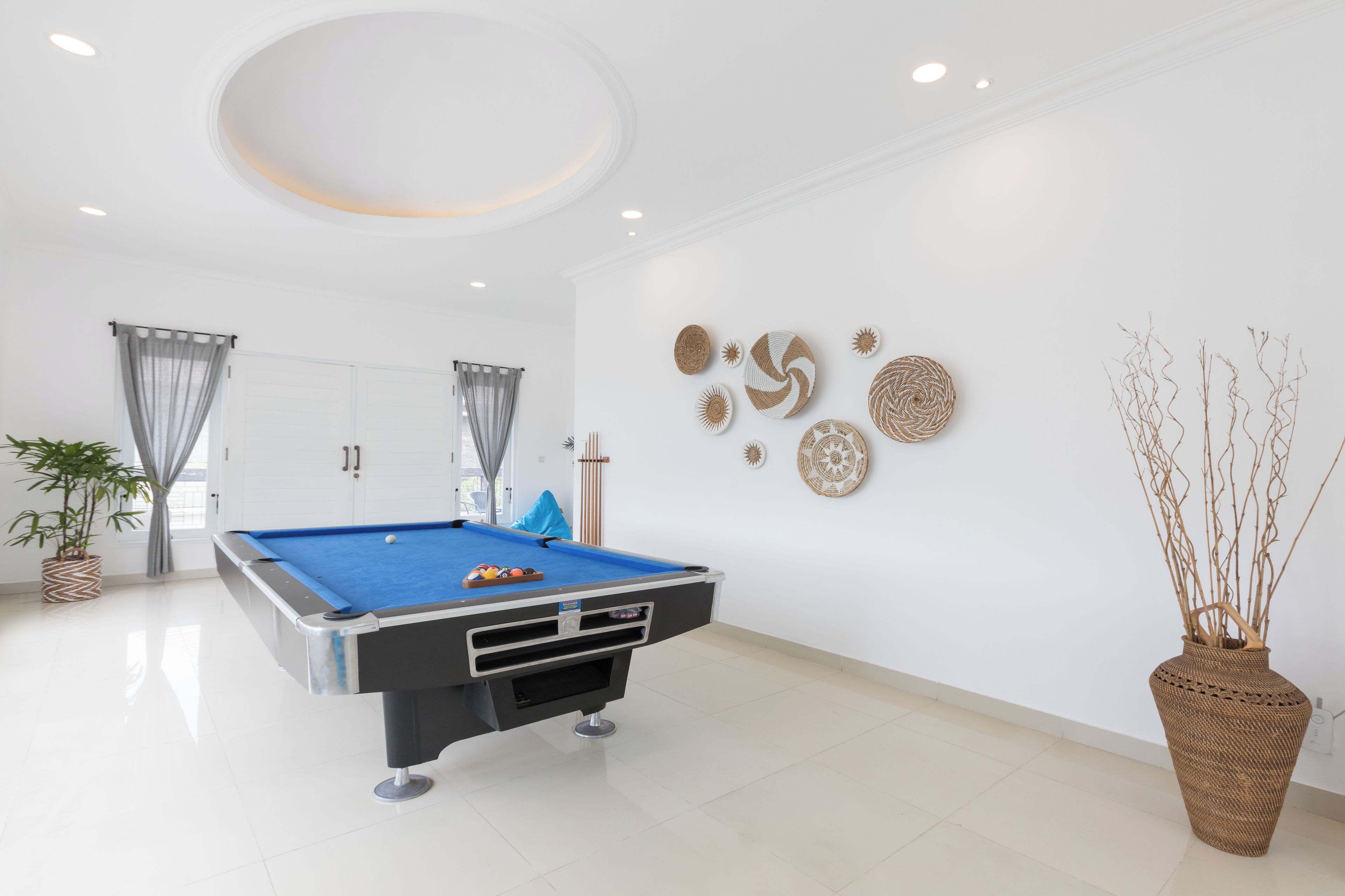 A modern room with a pool table, a large vase with branches, and decorative wall art.