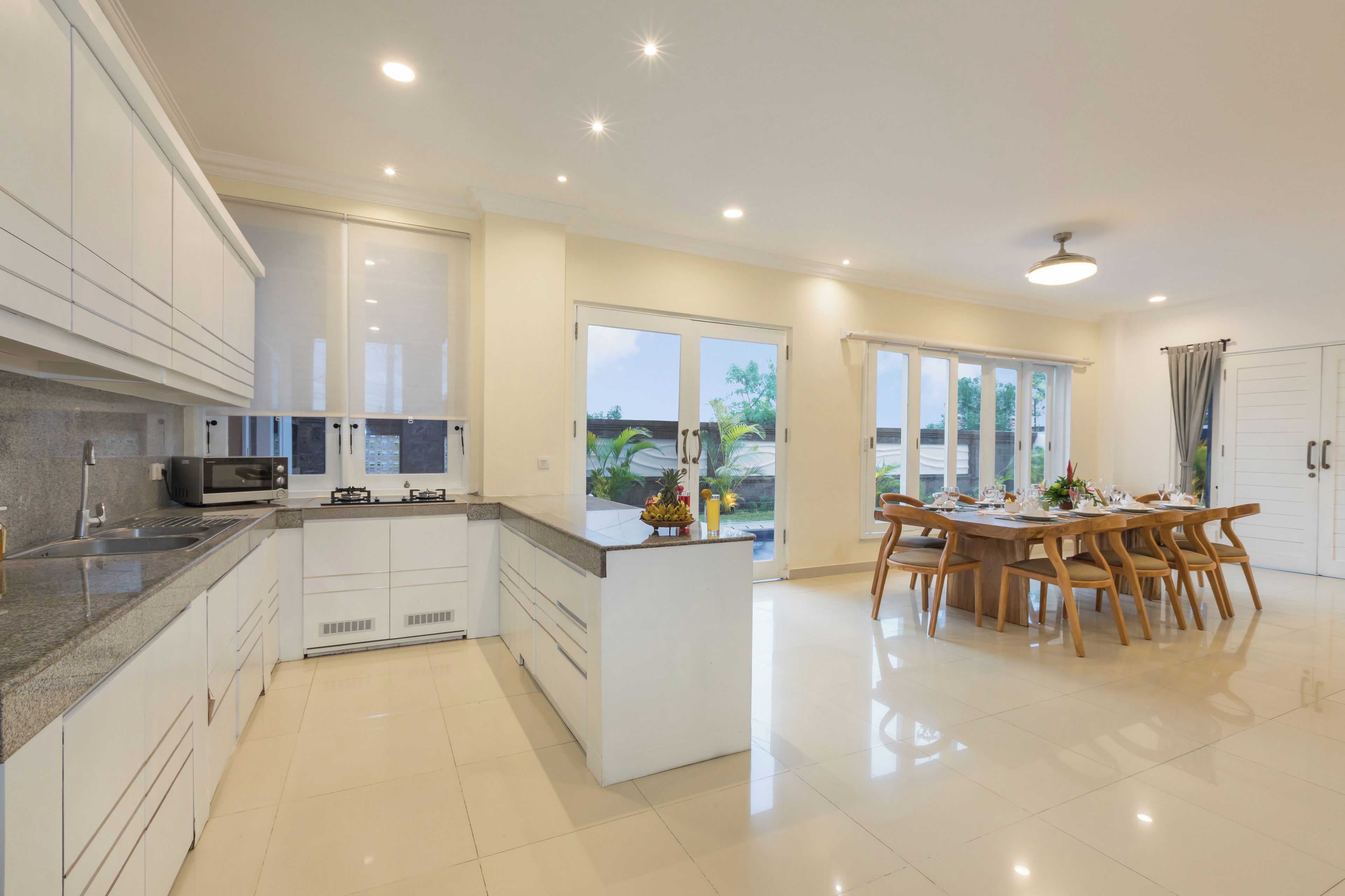 A modern kitchen with white cabinets, a granite countertop, and a dining area with wooden chairs and a table set for four.