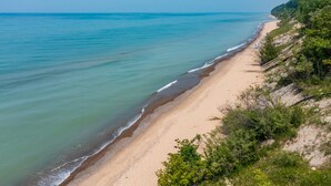 A coastal beach with a sandy shore and a forested cliff.