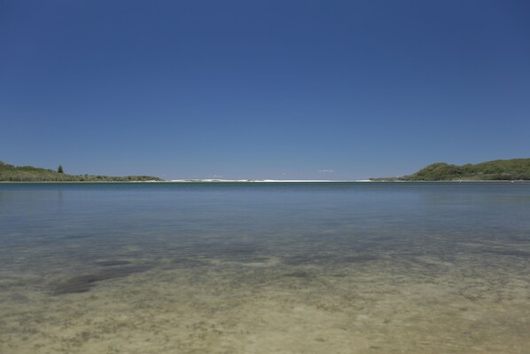 A clear view of a calm lake with a distant shoreline.
