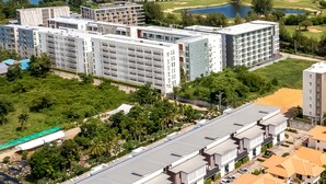 A modern hotel complex with multiple buildings, a golf course, and a beach in the background. - Pool villa  4 BR walking to Beach HV (Hua Hin)