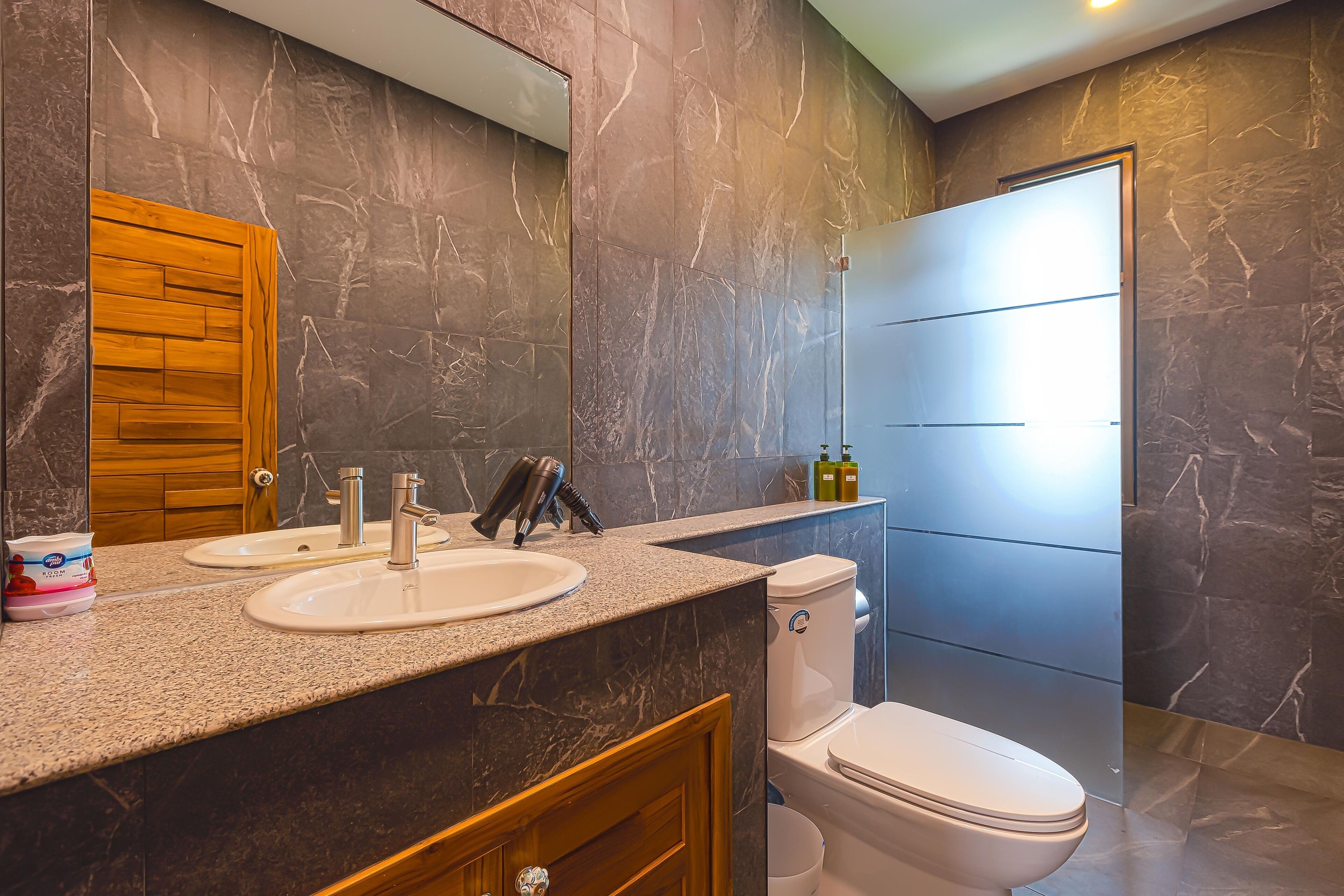 Een badkamer met twee wastafels, een toilet en een grote spiegel.
