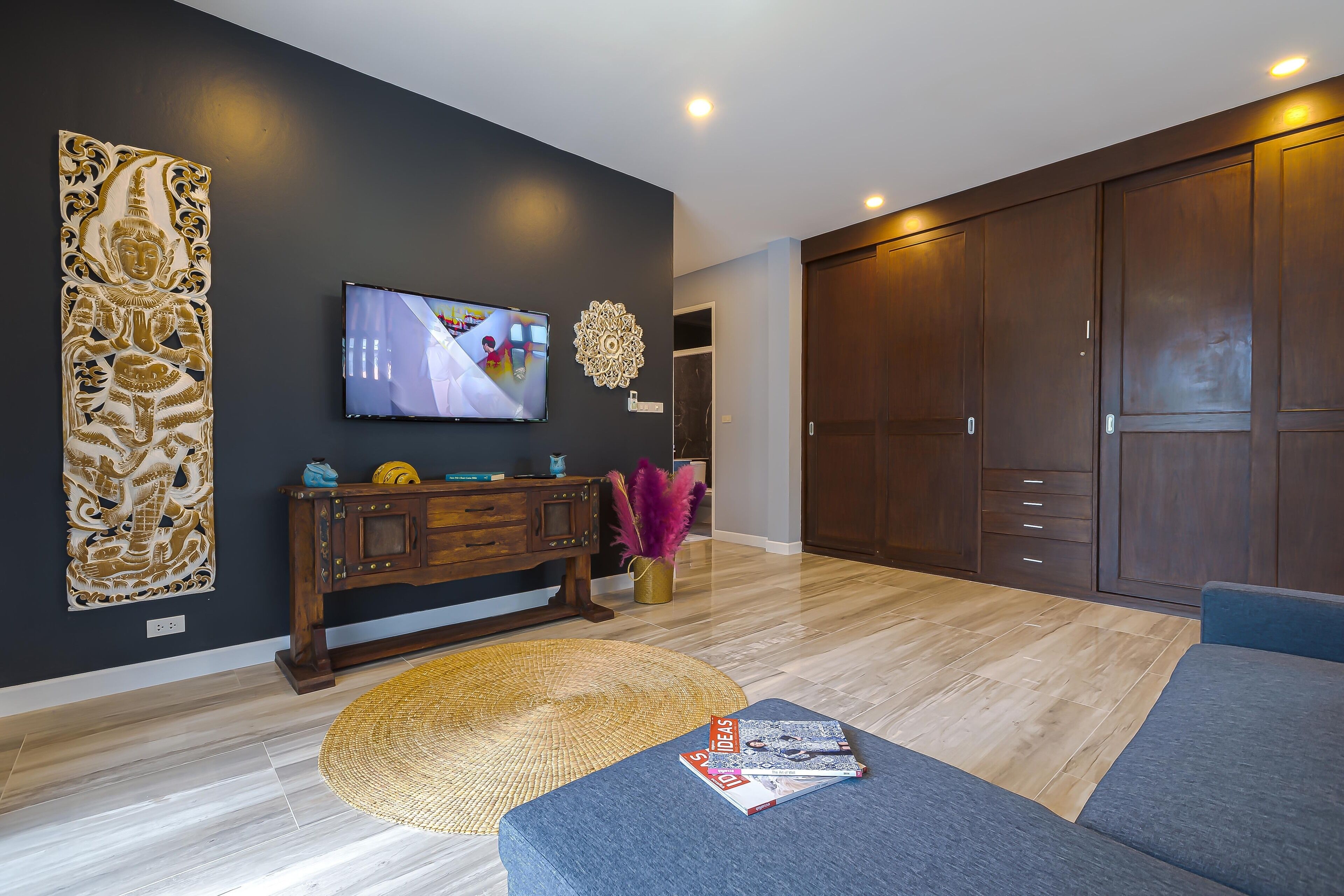 A modern living room with a dark wall, a wooden cabinet, a television, and a large wardrobe.