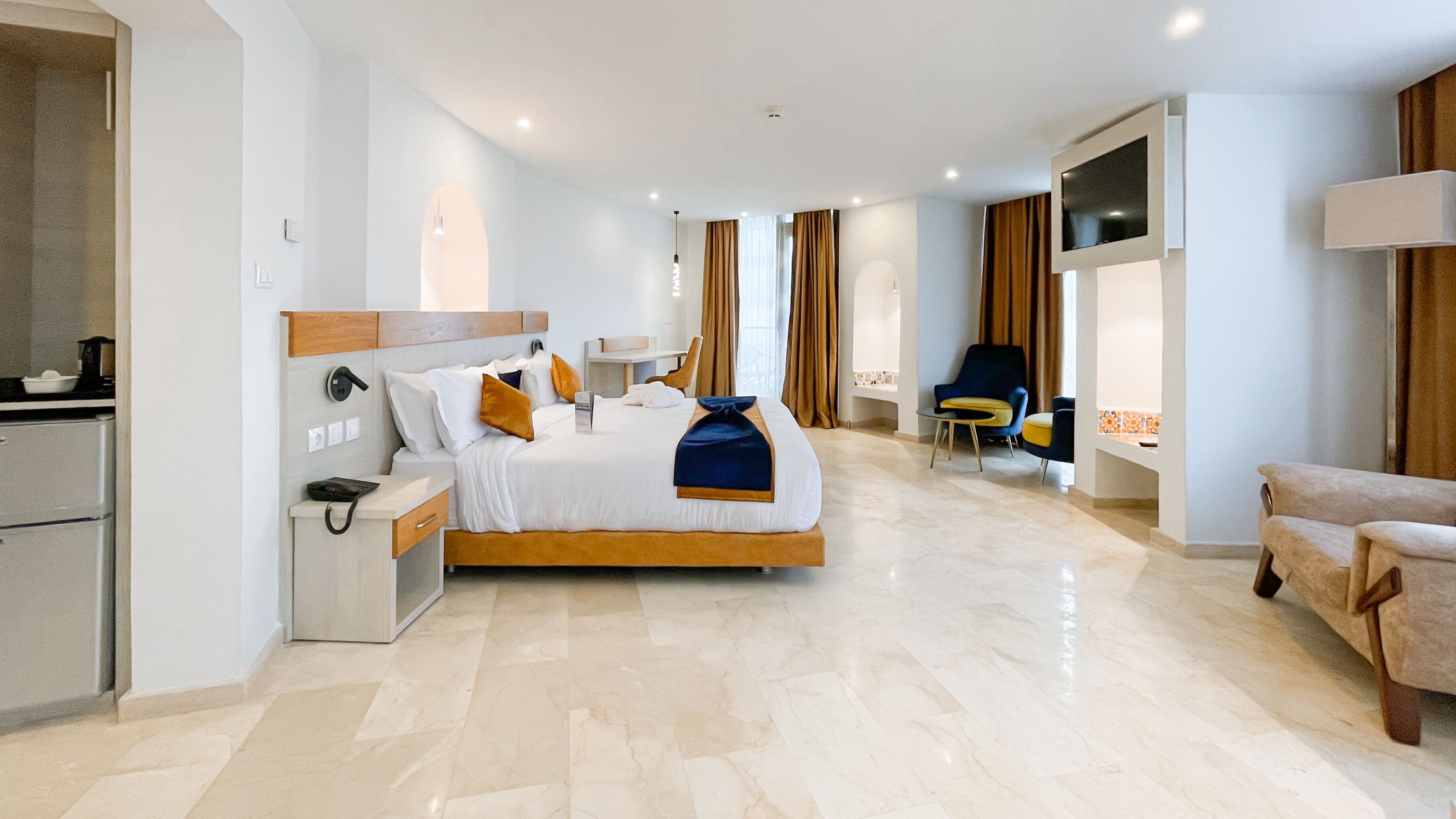 A modern hotel room with a large bed, a desk, a chair, and a TV.