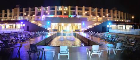 A modern hotel with a central courtyard, outdoor seating area, and a pool.