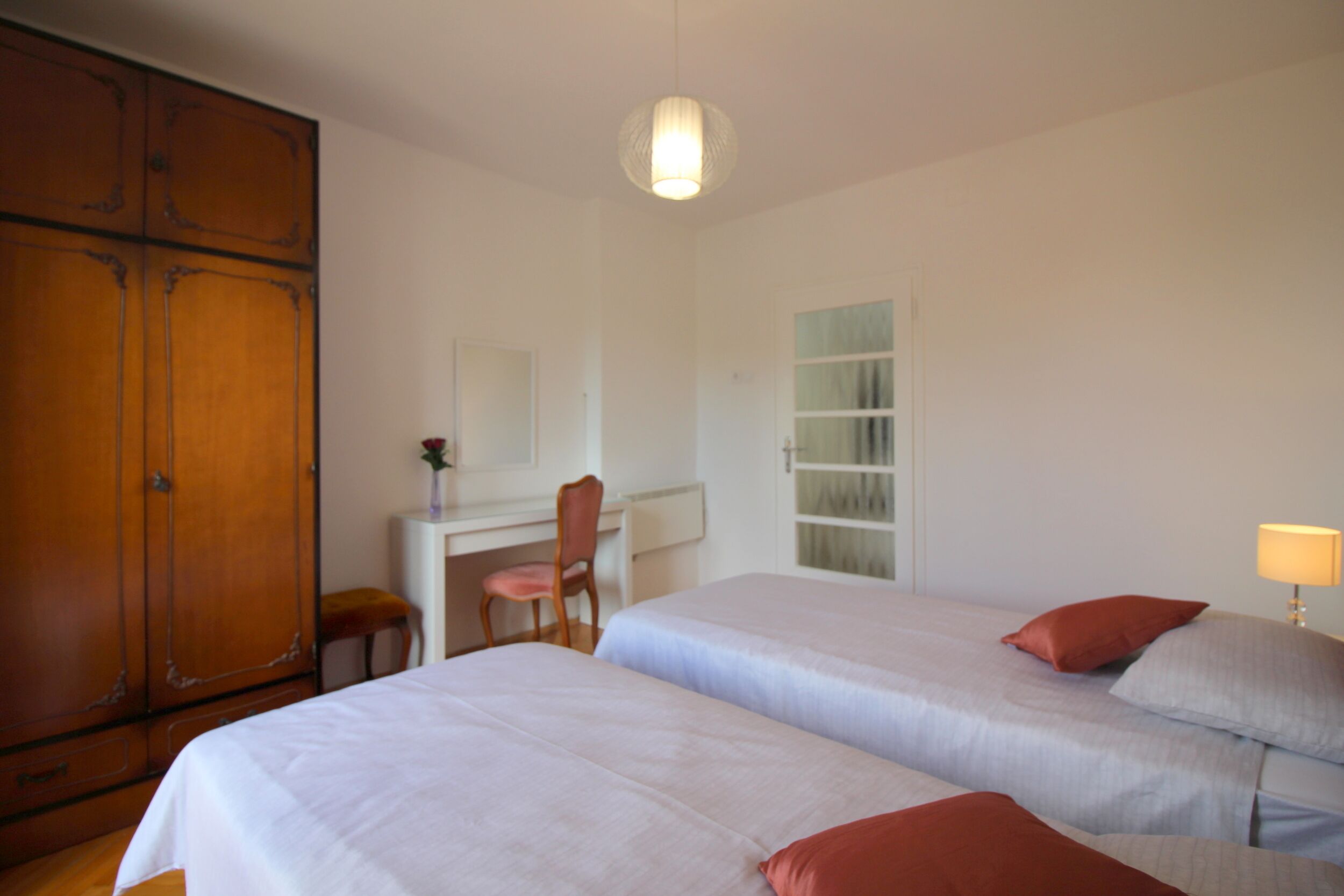 Ein Schlafzimmer mit zwei Betten, einem Schreibtisch, einem Stuhl und einem Kleiderschrank.