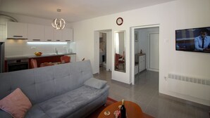 Un salon moderne avec un canapé gris, une petite table basse et un téléviseur fixé au mur.