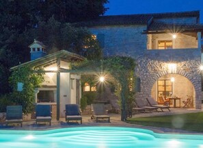 Un edificio de piedra con piscina, mobiliario exterior y una pérgola.
