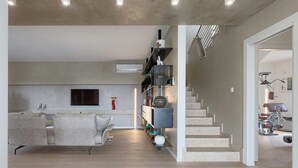 A modern living room with a sofa, a TV, a staircase, and a gym area. - Villa Laura (Stanišovi)