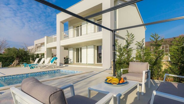 A modern two-story building with a pool, outdoor seating, and a view of the surrounding landscape. - Villa Laura (Stanišovi)