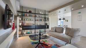 A modern living room with a sofa, a coffee table, a bookshelf, and a flat-screen TV. - Villa Laura (Stanišovi)