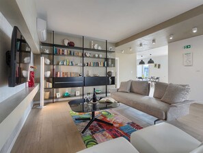 Una sala de estar moderna con un sofá, una mesa de centro, una estantería y un televisor de pantalla plana.