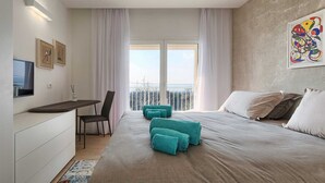 A modern hotel room with a bed, a desk, a chair, a TV, and a balcony with a view. - Villa Laura (Stanišovi)