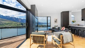 A modern living room with a large window overlooking a scenic mountain lake.
