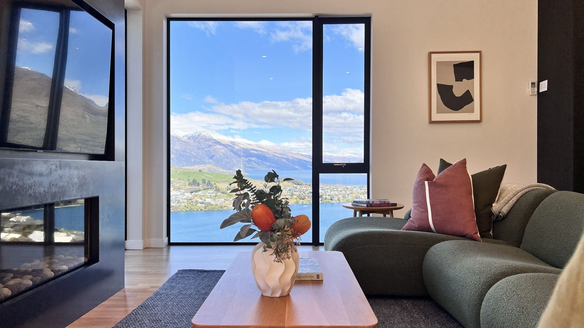 Ett modernt vardagsrum med ett stort fönster, en soffa, ett soffbord och en vas med blommor.